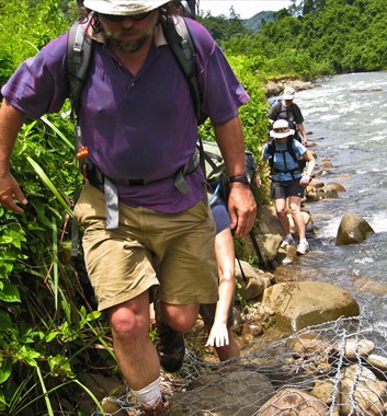 Borneo Trekking along edge of river in rainforest
